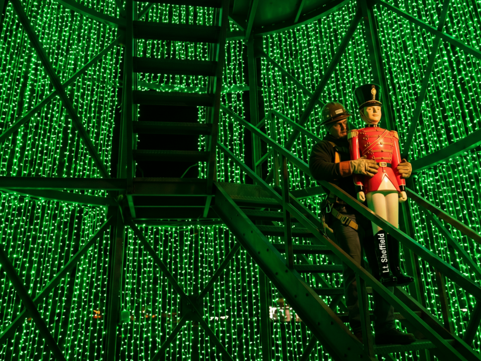 A worker carefully carrying a Toy Soldier ornament down from the Glory Tree after the season